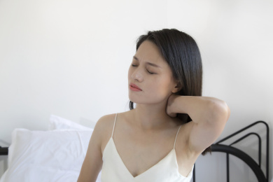 在床上一个颈椎痛的东方女人