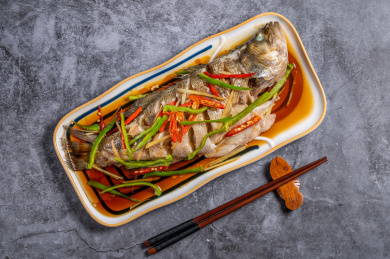 灰色背景上的一盘清蒸鲈鱼