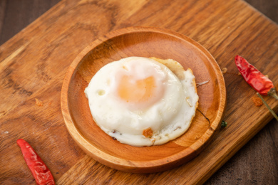 棕色木纹板上放着一碗煎荷包蛋