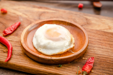 棕色木纹板上放着一碗煎荷包蛋