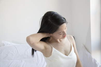 在床上一个颈椎痛的东方女人