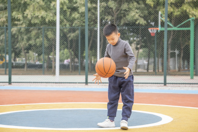 学校操场上打篮球的小男孩