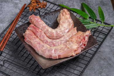 水泥背景烧烤网上的一盘生鸡脖