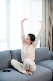 快乐的年轻女子沙发上伸展双手