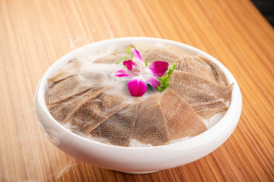 木纹桌上有一盘冰鲜毛肚火锅涮菜盖