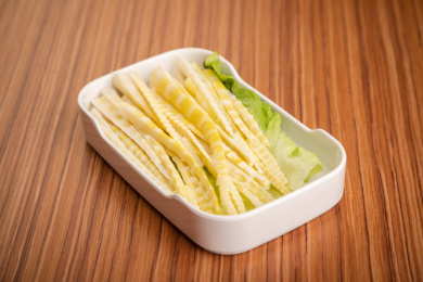 浅色木纹板上放着一盘嫩笋