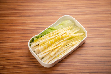 浅色木纹板上放着一盘嫩笋