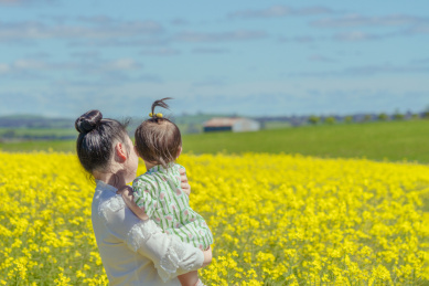 妈妈抱着小男孩看油菜花 