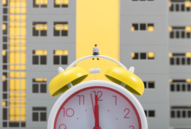 微缩创意住房与闹钟上思考的男性