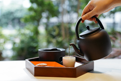 手拿黑色陶壶把茶水倒入茶杯中