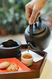 手拿黑色陶壶把茶水倒入茶杯中
