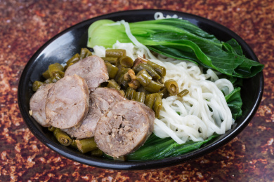 黑碗里腊肠菜蔬面条