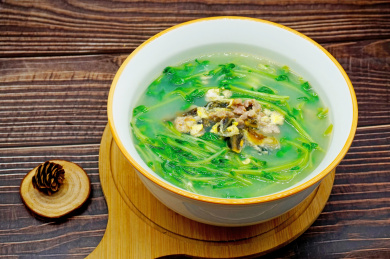 木桌背景一碗上汤豆苗特写