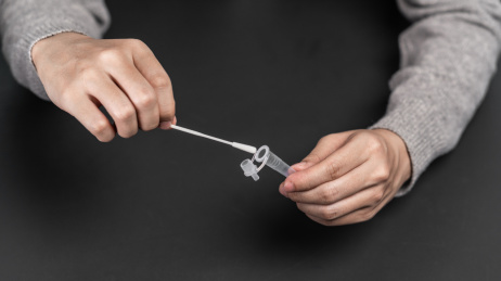 一只手正在将鼻拭子插入提取缓冲液管