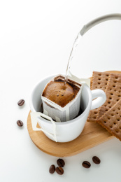 白色桌面上手冲壶正好在冲一杯挂耳咖啡