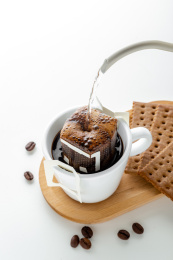 白色桌面上手冲壶正好在冲一杯挂耳咖啡