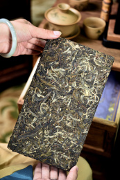 双手拿着一块普洱生茶大茶砖