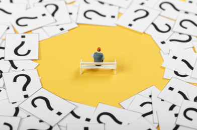 微缩创意问号堆里坐在长椅上思考的男性