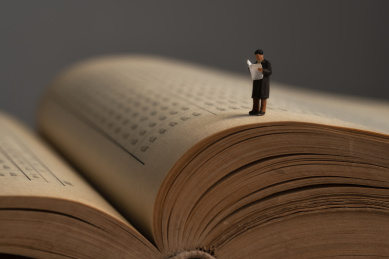 一个站在泛黄书本上看书读报的微缩创意