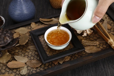 木质背景上往茶杯里倒茶水