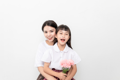 白背景前一对中国母女女儿给妈妈送康乃馨