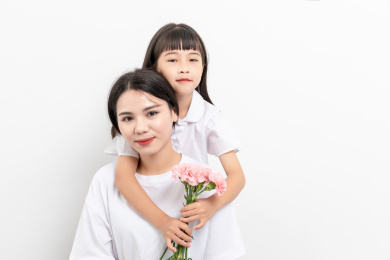 白背景前一对中国母女女儿给妈妈送康乃馨