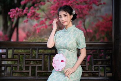 穿旗袍的女子拿着扇子坐在亭子里