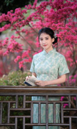 穿旗袍的女子在亭子旁看书