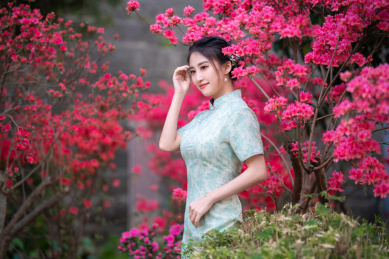 穿旗袍的女子站在花丛里