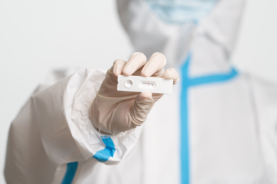 身穿防护服的医务人员手持阴性抗原检测卡