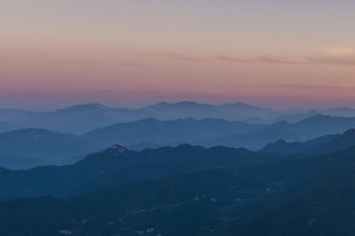 层层叠叠的山峦掩映在黎明的晨雾中