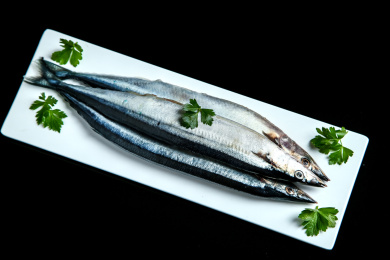 黑底上摆放着一盘秋刀鱼