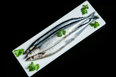 黑底上摆放着一盘秋刀鱼