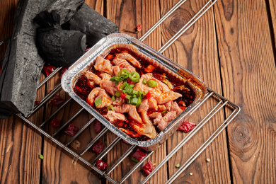 黑色餐盘上的冒着热气的炭烤鸭头 上面散落着一些葱花