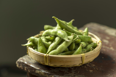 一簸箕毛豆角摆放在木桌面上特写深色调