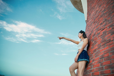 盛夏夕阳晚霞湖边码头灯塔上的少女