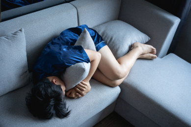 男子蜷缩在沙发上抱着抱枕