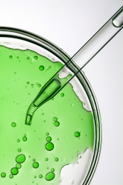 玻璃吸管吸取绿色液体的特写