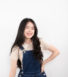 单手掐腰的可爱女生站在白色背景前