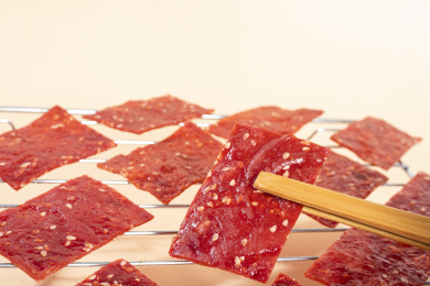 烤架上夹起的红色猪肉脯肉片