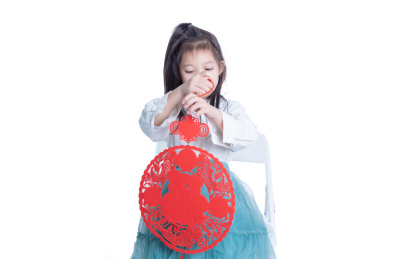 白色背景前拿着新年福字贴画的小女孩