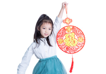 白色背景前拿着新年福字贴画的小女孩