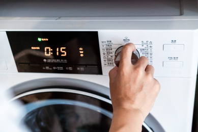 一只手正在选定洗衣机的洗涤模式