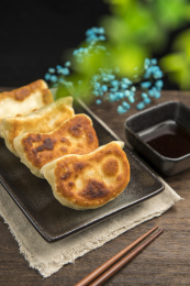 一盘素馅锅贴摆放在木桌面上特写