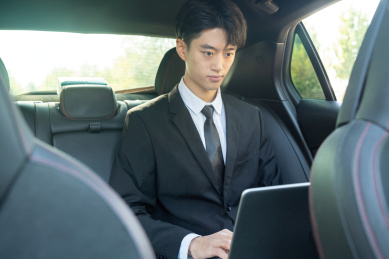 汽车后座使用电脑的西装商务男性
