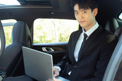 汽车后座使用电脑的西装商务男性