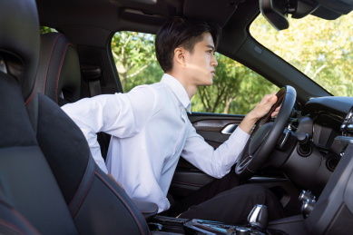 坐在车内腰酸背痛的年轻男性司机