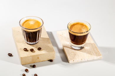 石板上有两杯浓缩咖啡和一些咖啡豆