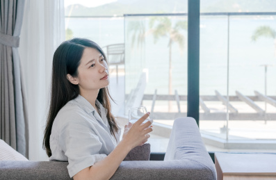 开心的女人坐在沙发上拿着一杯水