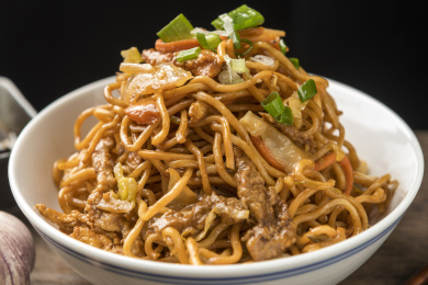 一碗炒面摆放在木桌面上特写